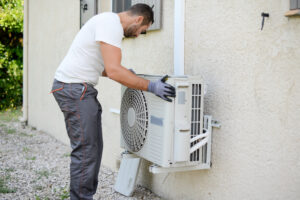 Home handsome young man electrician installing air conditioning in a client house